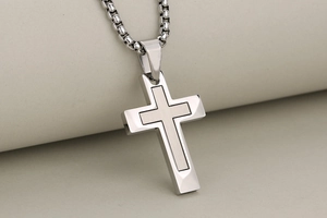 Detailed macro view of dual-layer stainless steel cross pendant with brushed and polished finish