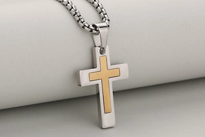 Detail of two-tone stainless steel cross pendant with brushed gold finish and box chain