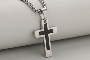 Macro side view of layered stainless steel cross pendant with silver and black finish