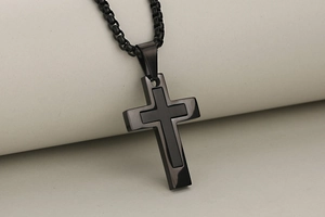 Macro detail of black stainless steel cross pendant with layered design and box chain link