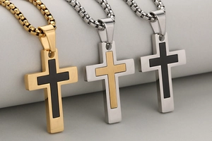Detailed view of three stainless steel cross pendants with polished and brushed finishes