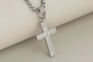 Detail of a stainless steel cross pendant featuring twelve inset zircons on a box chain