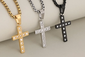 Close-up of gold, silver, and black stainless steel cross pendants with inlaid crystals