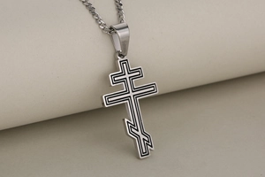 Detail of silver stainless steel Orthodox cross pendant with black enamel textures