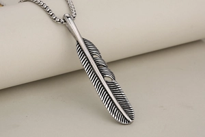Macro view of retro stainless steel feather pendant necklace with detailed engraving texture