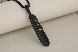 Macro detail of matte black feather pendant necklace with vintage engraved textures