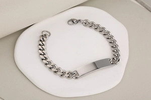 Macro detail of silver stainless steel Cuban chain bracelet with smooth rectangle ID plate
