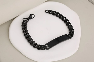Macro detail of black stainless steel Cuban link bracelet with polished ID nameplate