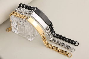 Detailed trio of polished ID bracelets in black, silver, and gold with Cuban chains