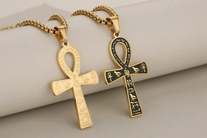 Close-up of gold Ankh cross pendants with Egyptian hieroglyphs and black enamel details