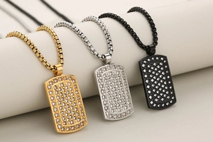 Close-up of iced out dog tag pendants in gold, silver, and black with box chains