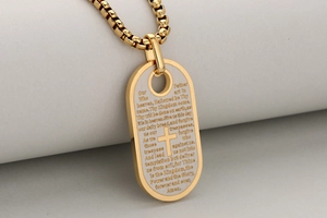 Detail van de goud- en zilverkleurige stalen dogtag met kruis en gegraveerd gebed