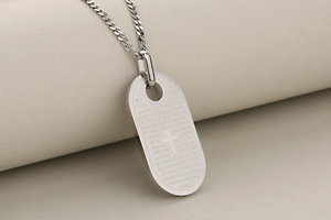 Detailopname van de roestvrijstalen dog tag hanger met gegraveerd kruis en gebed