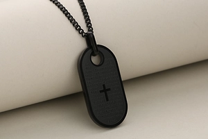 Detailopname van zwarte roestvrijstalen dogtag ketting met kruisgravure en tekst van Onze Vader