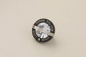 Detail of round stainless steel pendant with crystal and 'Thank you for your love' engraving