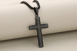 Dettaglio del ciondolo a croce in acciaio inossidabile nero opaco su supporto per gioielli