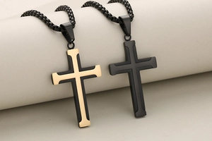 Dettaglio dei ciondoli a croce in acciaio inossidabile bicolore oro e nero con catena box