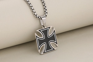 Detail of a vintage stainless steel cross pendant with black oil drip and box chain