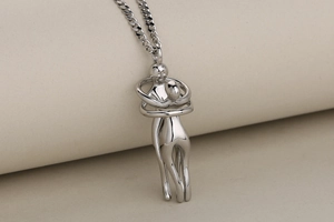 Detalle de collar con colgante de abrazo en plata pulida sobre soporte minimalista