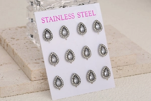 Macro shot of 11 pairs of stainless steel teardrop earrings with crystals on display