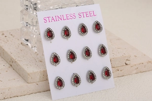 Close-up of 6 pairs of stainless steel teardrop earrings with red stones and crystals