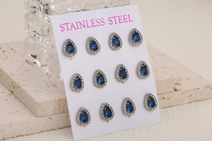 Macro detail of 12 pieces teardrop stainless steel studs with blue stones on card