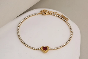 Vista macro de la pulsera de acero inoxidable dorado con circón rojo en forma de corazón