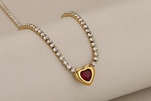 Gros plan d'un collier doré avec pendentif cœur rouge et pierres de cristal brillantes