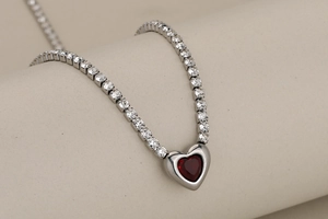 Détail macro du collier tennis argenté avec une pierre précieuse rouge en forme de cœur