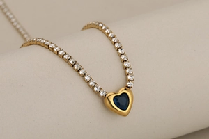 Gros plan du collier cœur avec pierre saphir bleu sur une chaîne tennis dorée