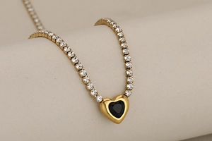 Détail du pendentif cœur en onyx noir avec bordure dorée sur une chaîne de tennis chic