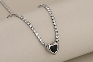 Détail macro d'un collier rivière argenté avec un pendentif en pierre noire en cœur
