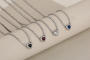 Détail de colliers tennis cœur en cristal noir, rouge, blanc et bleu sur support élégant