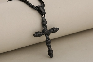 Dettaglio ravvicinato di un ciondolo a croce nero opaco con trama a corda su catena box