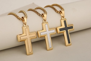 Dettaglio di ciondoli a croce bicolore in acciaio inossidabile oro, argento e nero