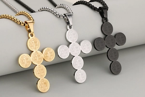 Detailed view of St. Benedict cross pendants in gold, silver, and black finishes