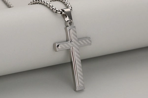 Close-up of double-layer stainless steel cross pendant with textured striped detail