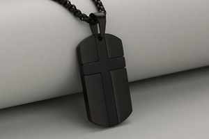 Makroaufnahme von matt schwarzem Edelstahl-Hundemarken-Anhänger mit 3D-Kreuz und Box-Halskette