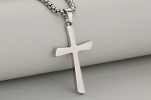 Close-up of a silver polished stainless steel cross pendant with a box chain necklace