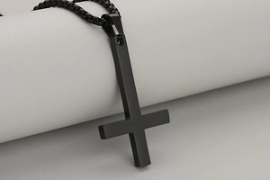 Detail van matzwarte minimalistische omgekeerde kruishanger met bijpassende kralenketting