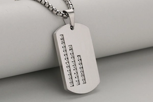 Detail of brushed stainless steel military pendant with zircon inlay and box chain