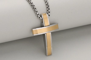 Macro detail of two-tone stainless steel cross pendant with brushed gold texture