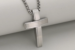 Macro shot of silver stainless steel 3D cross pendant with brushed and polished texture