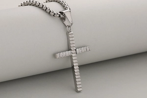 Detalle macro de colgante de cruz de acero inoxidable para hombre con diseño de ondas