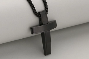 Detail of a matte black stainless steel cross pendant with industrial layered design