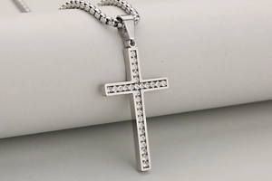 Macro-opname van zilveren kruishanger met glanzende stenen en een box ketting