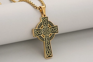 Détail macro du pendentif croix celtique dorée avec émail noir et chaîne vénitienne
