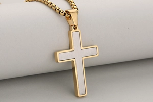 Macro shot of two-tone gold and silver religious cross pendant with box chain detail