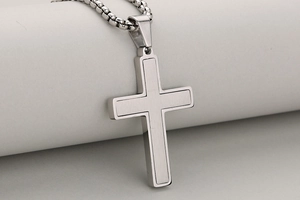 Detail shot of a brushed stainless steel cross pendant on a sturdy silver box chain