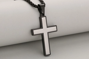 Detail of cross pendant featuring brushed silver inlay and black stainless steel base